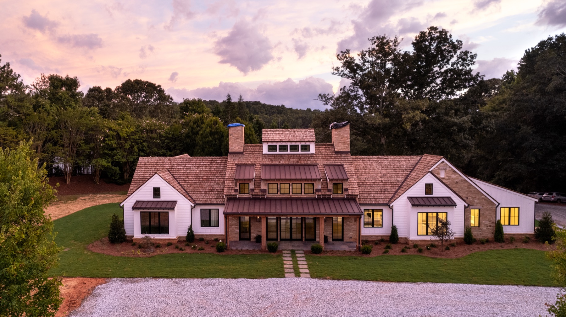 Estate home lit at dusk behind a gravel motor court