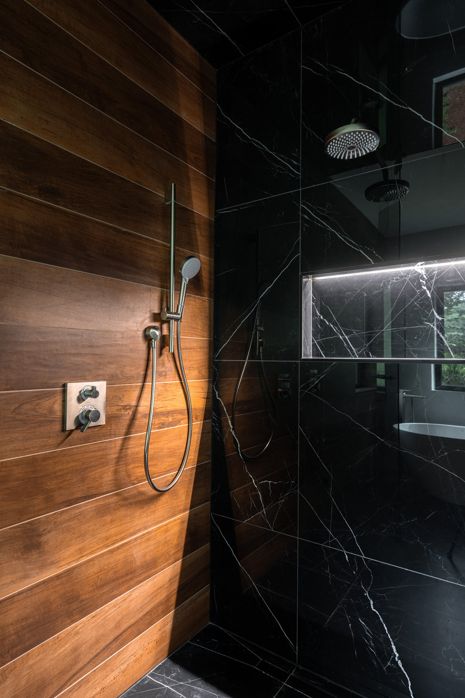 Primary bathroom with walnut paneling and black marble shower